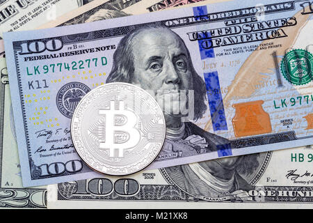 Silber bitcoin auf hundert Banknoten Hintergrund. Stockfoto