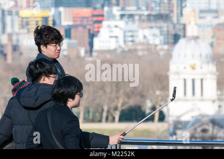 Asiatische Touristen mit einem selfie Stick ein selfie in Greenwich vor der Blick über die Themse zu nehmen Stockfoto