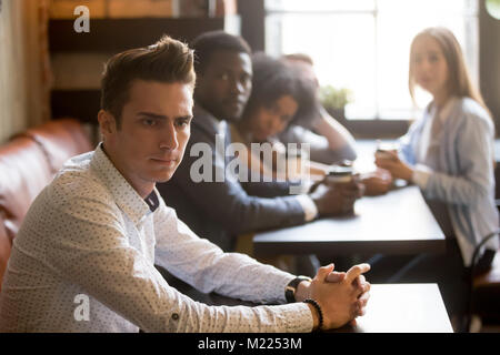 Diverse Freunde bei frustrierter Mann allein sitzen im Cafe suchen Stockfoto