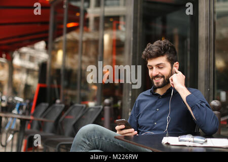 American Boy Musik im Cafe mit Ohrhörer und smart Stockfoto