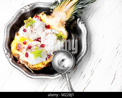 Eis in der Ananas Schüssel, dekoriert mit Kiwi und Granatapfel. Eis Dessert Stockfoto