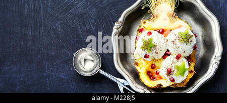 Eis in der Ananas Schüssel, dekoriert mit Kiwi und Granatapfel. Eis Dessert Stockfoto