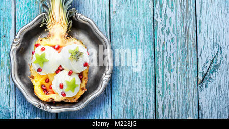 Eis in der Ananas Schüssel, dekoriert mit Kiwi und Granatapfel. Eis Dessert Stockfoto