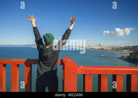 SAN FRANCISCO, USA - ca. November 2017: Teen Girl mit erhobenen Händen auf die Golden Gate Bridge Stockfoto