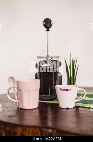 Französische Presse mit schwarzem Kaffee und eine Tasse und Kaffee Tasse auf einem Holztisch Stockfoto