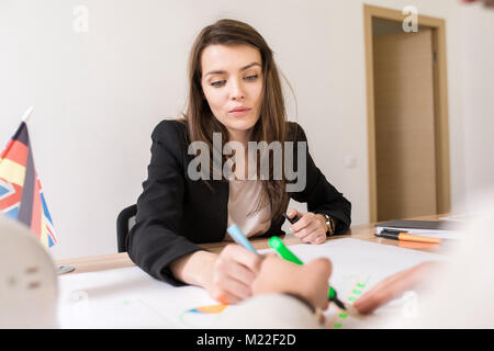 Porträt der schönen Geschäftsfrau Ausarbeitung Pläne am Schreibtisch sitzen in internationalen Agentur Stockfoto