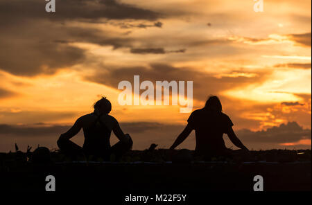 Yoga am Strand während einer spektakulären Sonnenuntergang Stockfoto