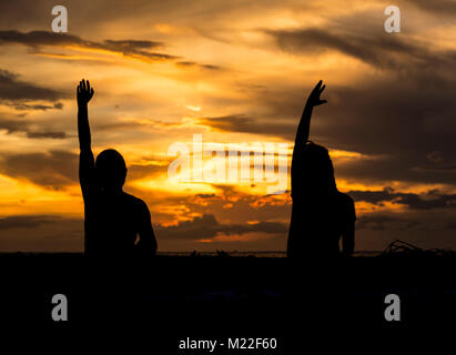 Yoga am Strand während einer spektakulären Sonnenuntergang Stockfoto