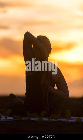 Yoga am Strand während einer spektakulären Sonnenuntergang Stockfoto