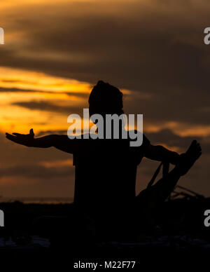 Yoga am Strand während einer spektakulären Sonnenuntergang Stockfoto