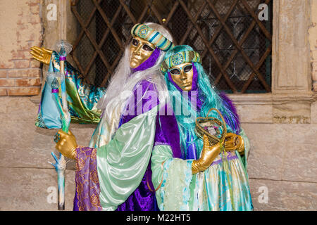 Paar schöne venezianische Masken in bunten und eleganten Kostüm auf dem Markusplatz in Venedig. Stockfoto