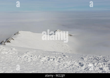 Verschneite Berge und Wolken. Blick von der Spitze des Berges. Stockfoto