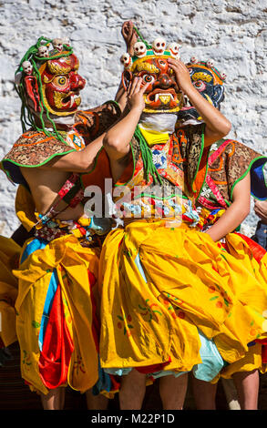 Prakhar Lhakhang, Bumthang, Bhutan. Zwei buddhistische Mönche tragen Masken von einer mythologischen Gottheit Einstellen der Maske eines anderen vor der Durchführung einer Tanz in Stockfoto