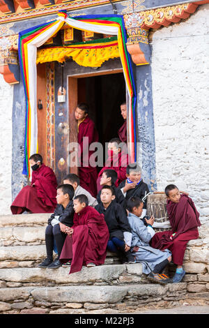 Prakhar Lhakhang, Bumthang, Bhutan. Junge buddhistische Mönche in Tür und auf Kloster Schritte Beobachten ältere Mönche eine Tanz in der Duechoed Relig Stockfoto