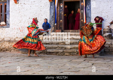 Prakhar Lhakhang, Bumthang, Bhutan. Junge buddhistische Mönche in Kloster Tür gerade älteren Mönche tragen Masken der mythologischen Gottheiten, während Pro Stockfoto