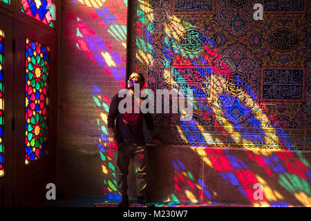 Ein Tourist steht in das Licht, das durch die Stain Glass Windows der Nasir al Molk Moschee in Shiraz, Iran kommenden Stockfoto