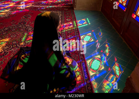 Ein Tourist sitzt in das Licht, das durch die Stain Glass Windows der Nasir al Molk Moschee in Shiraz Stockfoto