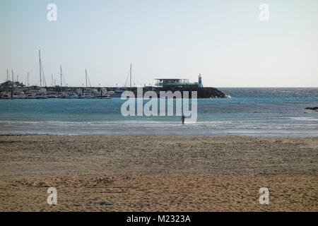 Einsame Mann Waten in das Meer vom Strand bis zum Yachthafen in Costa Caleta de Fuste, Fuerteventura, Kanarische Inseln, Spanien, EU. Stockfoto