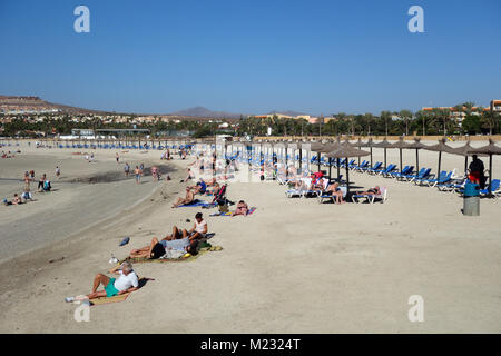 Sonnenanbeter in der Sonne liegend durch Leere Liegestühle an der Costa Caleta de Fuste Strand auf Fuerteventura auf den Kanarischen Inseln, Spanien, EU. Stockfoto