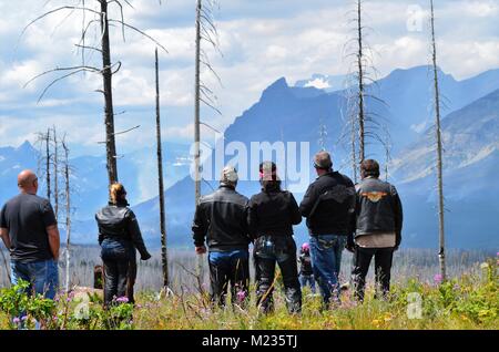 Ein Wald Feuer brennt in vielen Gletschern, Montana weit im Inneren des Berges, während eine Gruppe von Motorrad Biker weiter aus der ferne Blick Stockfoto