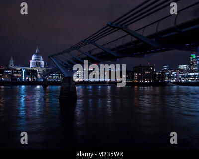 Die St Paul's Kathedrale bei Nacht mit der Millennium Bridge im Vordergrund. Stockfoto