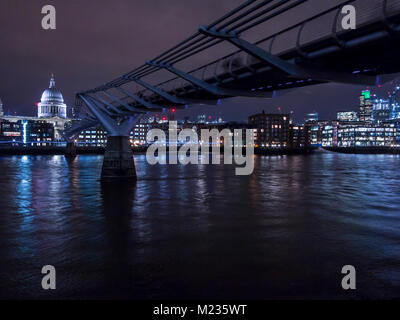 Die St Paul's Kathedrale bei Nacht mit der Millennium Bridge im Vordergrund. Stockfoto