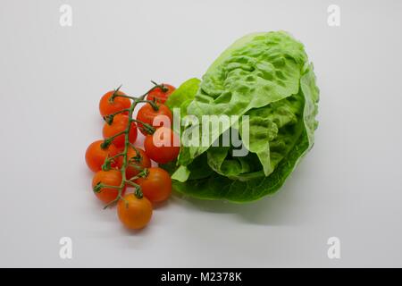 Cherry Tomaten (Solanum Lycopersicum) neben einem kleinen Juwel, Kopfsalat (Lactuca sativa) auf weißem Hintergrund Stockfoto