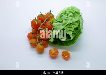 Cherry Tomaten (Solanum Lycopersicum) neben einem kleinen Juwel, Kopfsalat (Lactuca sativa) auf weißem Hintergrund Stockfoto