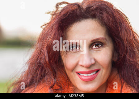 Nahaufnahme von einem schönen Lächeln, reife Frau mit Falten und roten Haar zu tragen orange Pelz Kragen Stockfoto