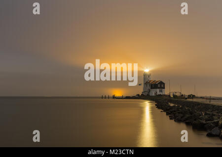 Leuchtturm bezeichnet das Pferd der Marken leuchtet den Nachthimmel über das IJsselmeer, Niederlande. Mit Lichtreflexion auf der Wasseroberfläche. Stockfoto