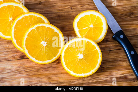 Orangenscheiben auf Küche aus Holz mit Kochmesser Stockfoto