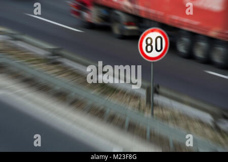 Defokussierten Bild von Verkehrszeichen mit 80 km/h Höchstgeschwindigkeit auf einer Autobahn mit roten Lkw im Hintergrund fahren Stockfoto