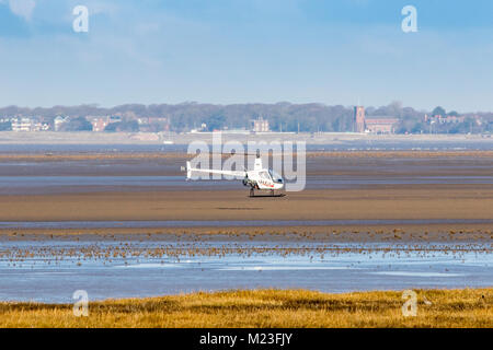 Ein Robinson R-22 Beta II, 2 Sitzer Kolben angetriebenen Hubschrauber Landung am Strand in Southport, Merseyside, UK. Stockfoto