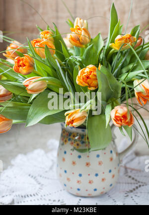 Ein Bündel von frischem orange Tulpen Blumen in einer Keramik Krug. Rustikaler Stil, selektiven Fokus Stockfoto