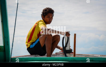 Lombok, Indonesien - 19.April 2016. Ein Junge auf Holz- Boot in Lombok, Indonesien sitzen. Lombok, Insel neben Bali, wo der Tourismus noch in der Stockfoto