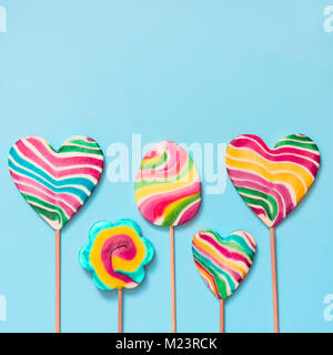 Satz von fünf Rainbow bunte Lollipops auf blauem Hintergrund isoliert. Lustiges Konzept. Ansicht von oben. Quadratisches Bild. Stockfoto