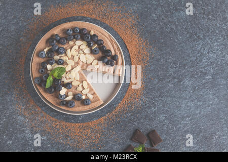 Raw vegan Schokolade - Karamell Käsekuchen mit Heidelbeeren, rohe Süßigkeit Kugeln und Mandeln. Gesunde vegane Ernährung Konzept. Stockfoto