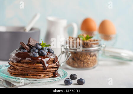 Schokolade Pfannkuchen mit Sirup und Beeren, Schokolade Müsli, Milch und Eier. Frühstück Konzept Stockfoto