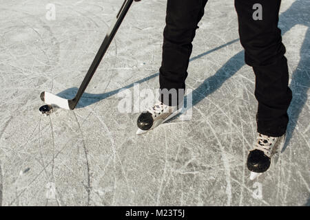 7/8 Bild von einem Mann, der Schlittschuhe Holding einen Stock und einen Puck Stockfoto