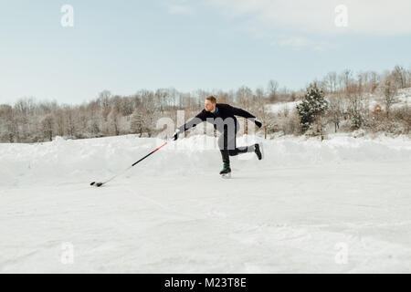 Mann spielt Eishockey auf einem zugefrorenen See Stockfoto