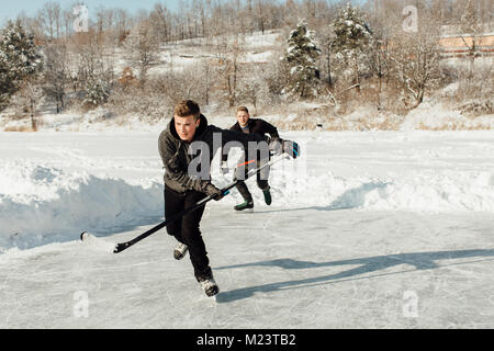 Zwei Männer spielen Eishockey auf einem zugefrorenen See Stockfoto