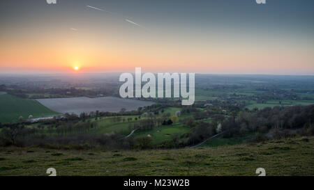 Die Sonne geht über Felder und Dörfer in die landwirtschaftliche Landschaft des Aylesbury Vale, aus Coombe Hill an der Steilkante des Chiltern Hills gesehen. Stockfoto