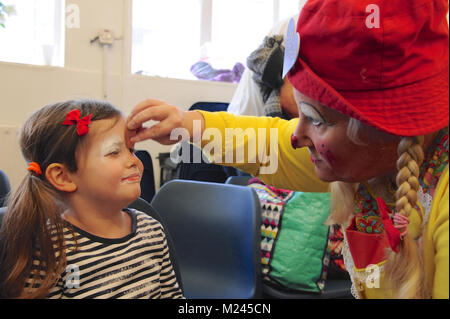 Dee Dee der Clown Anwendung Make-up mit einem kleinen Kind kurz vor dem 72. jährlichen Grimaldi Clown Gottesdienst in Alle Angaben zum Heiligen Kirche, Hackney, London, Vereinigtes Königreich. Der Service, der zu einer jährlichen Tradition seit 1946, wird in Erinnerung an Joseph "Joey" Clown Grimaldi (1778-1837), der am meisten gefeierten englischen Clown, geboren wurde und in London durchgeführt. Die einzigartige Gottesdienst ist an jedem ersten Sonntag im Februar statt und einen Kranz zu Ehren der Grimaldi. Quelle: Michael Preston/Alamy leben Nachrichten Stockfoto
