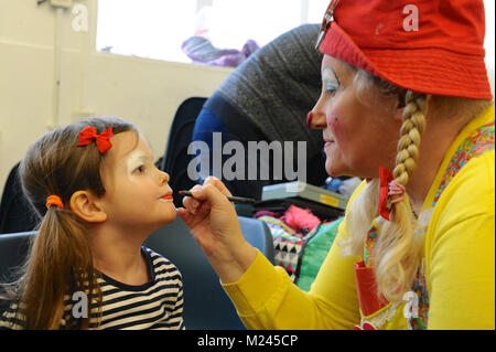 Dee Dee der Clown Anwendung Make-up mit einem kleinen Kind kurz vor dem 72. jährlichen Grimaldi Clown Gottesdienst in Alle Angaben zum Heiligen Kirche, Hackney, London, Vereinigtes Königreich. Der Service, der zu einer jährlichen Tradition seit 1946, wird in Erinnerung an Joseph "Joey" Clown Grimaldi (1778-1837), der am meisten gefeierten englischen Clown, geboren wurde und in London durchgeführt. Die einzigartige Gottesdienst ist an jedem ersten Sonntag im Februar statt und einen Kranz zu Ehren der Grimaldi. Quelle: Michael Preston/Alamy leben Nachrichten Stockfoto