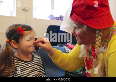 Dee Dee der Clown Anwendung Make-up mit einem kleinen Kind kurz vor dem 72. jährlichen Grimaldi Clown Gottesdienst in Alle Angaben zum Heiligen Kirche, Hackney, London, Vereinigtes Königreich. Der Service, der zu einer jährlichen Tradition seit 1946, wird in Erinnerung an Joseph "Joey" Clown Grimaldi (1778-1837), der am meisten gefeierten englischen Clown, geboren wurde und in London durchgeführt. Die einzigartige Gottesdienst ist an jedem ersten Sonntag im Februar statt und einen Kranz zu Ehren der Grimaldi. Quelle: Michael Preston/Alamy leben Nachrichten Stockfoto