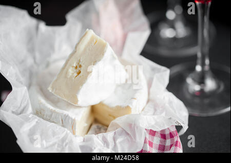 Brie Käse und Wein Gläser. Makro Bild, schwarzer Hintergrund. Horisontal. Stockfoto