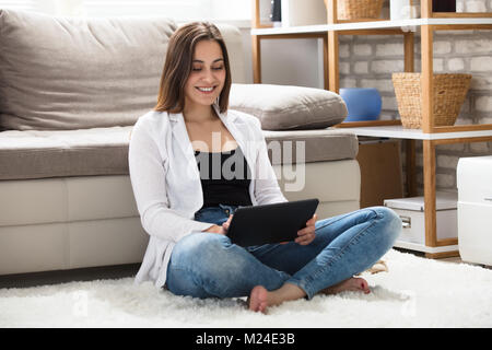Lächelnd schöne Frau mit digitalen Tablette zu Hause Stockfoto