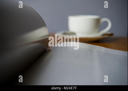 Öffnen Magazin auf einem verschwommenen Hintergrund mit einer Tasse Kaffee. Das Magazin ist auf dem Schreibtisch im Büro. Stockfoto