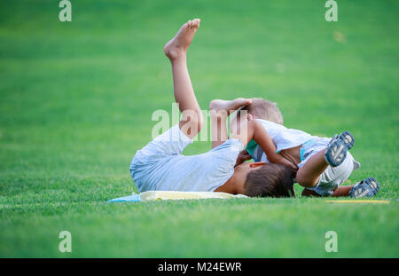 Zwei Jungen kämpfen im Freien. Geschwister wrestling auf Gras im Sommer Park. Geschwister Rivalität. Stockfoto