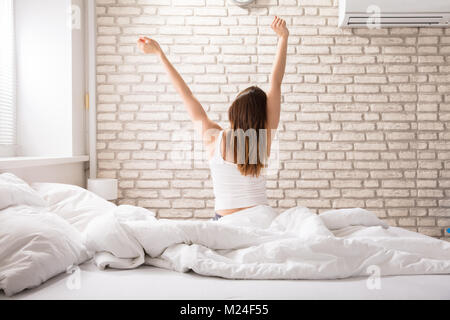 Rückansicht einer Frau, die Ihre Hände Dehnen beim Gehen bis auf das Bett Stockfoto